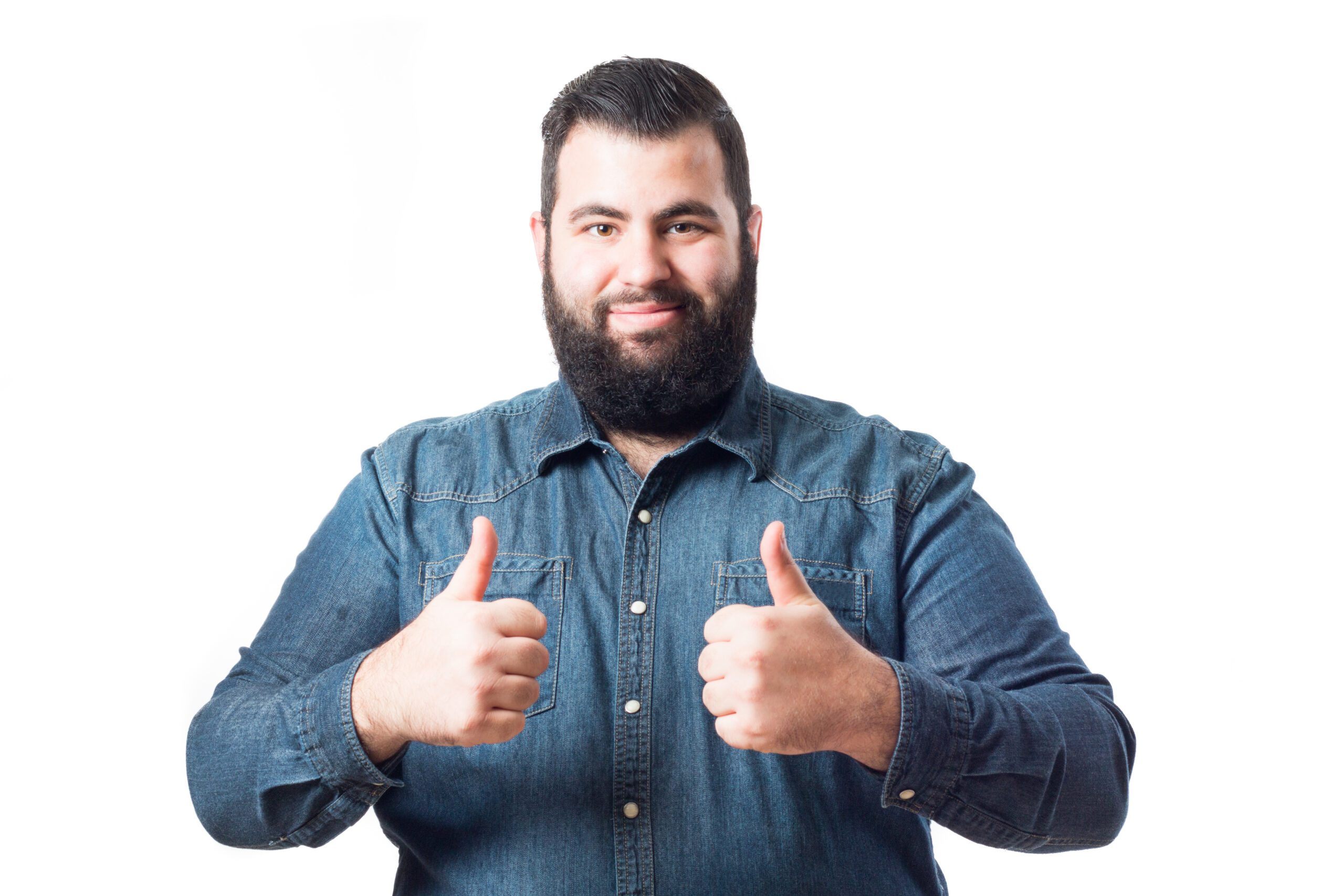 A man in a denim shirt smiling an holding two thumbs up.